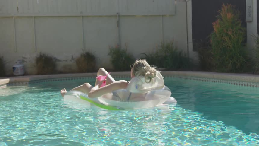 A woman sunbathing on a floating lounge chair in a pool