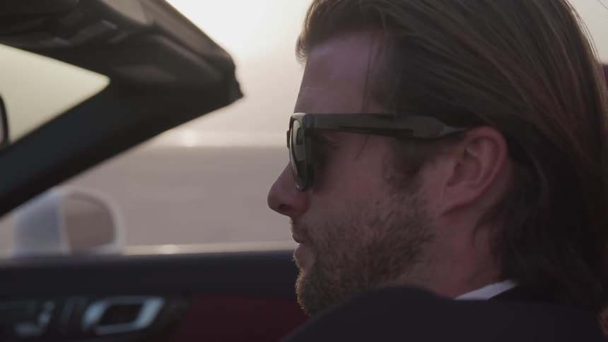 A man is driving in his convertible