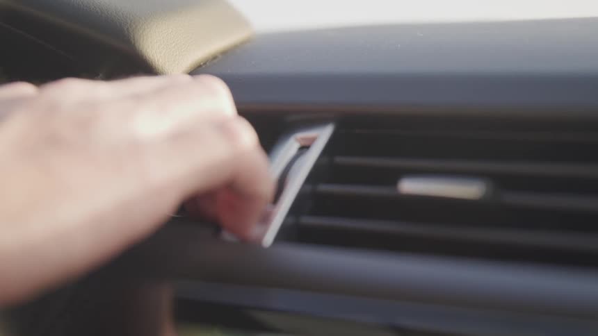 Person pushes start button on dashboard of car