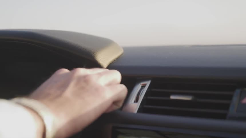 A person uses the push to start button in a newer car