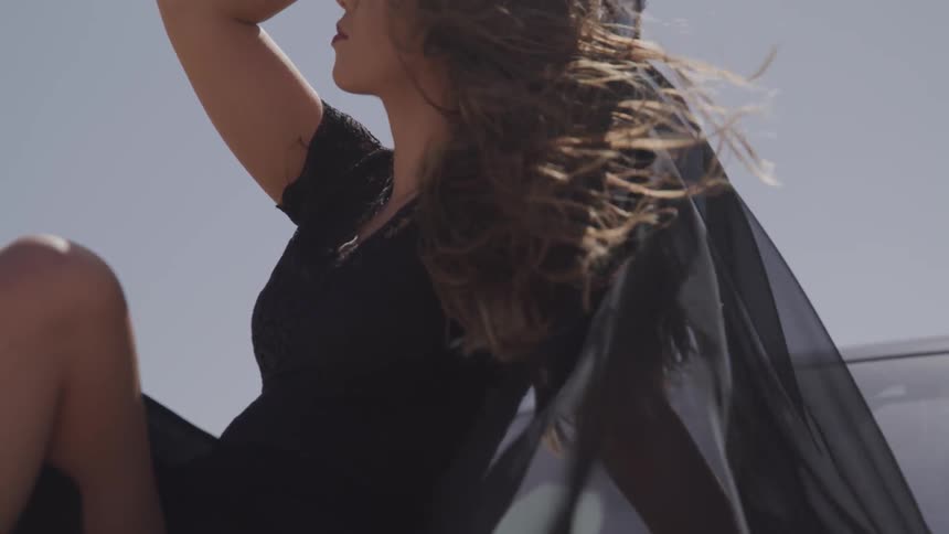 Black dressed woman sit georgeously while wind blows