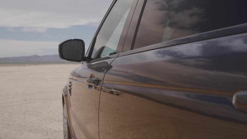 A dark blue vehicle is parked in the desert