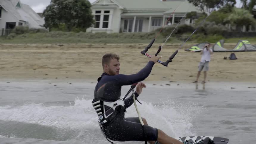 A man is parasailing int he water on a cloudy day