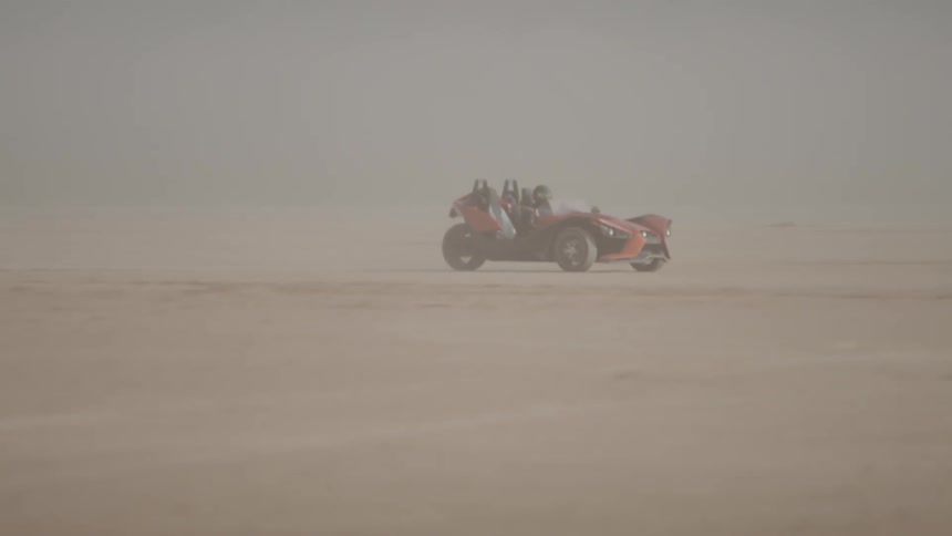 A polaris slingshot being driven through the desert