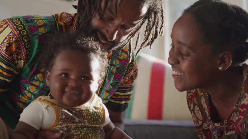 Parents play with their toddler as he laughs