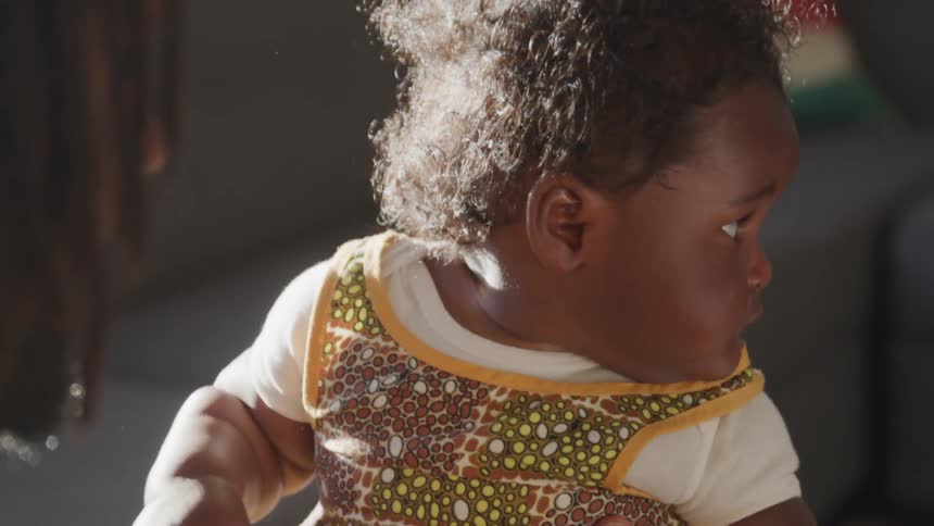 Black toddler being carried by her mother