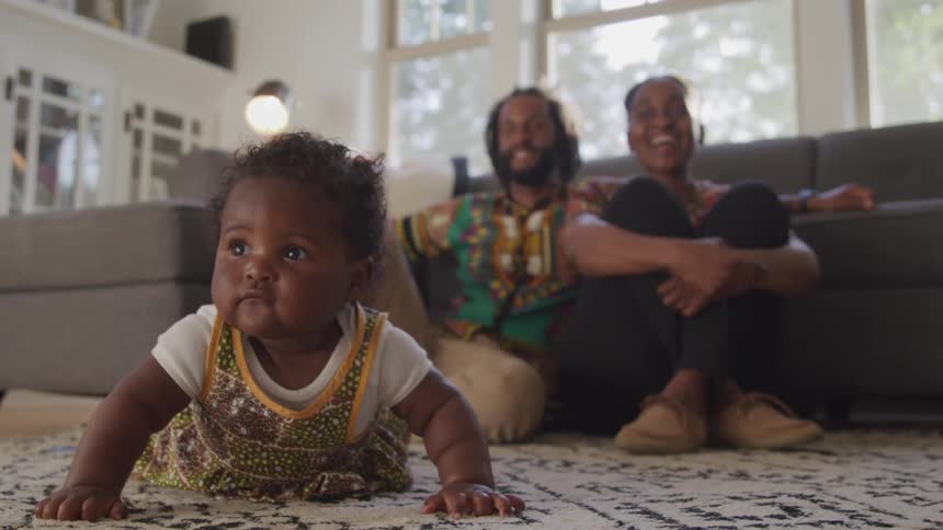 A black man woman and child relaxing on the floor in a living room