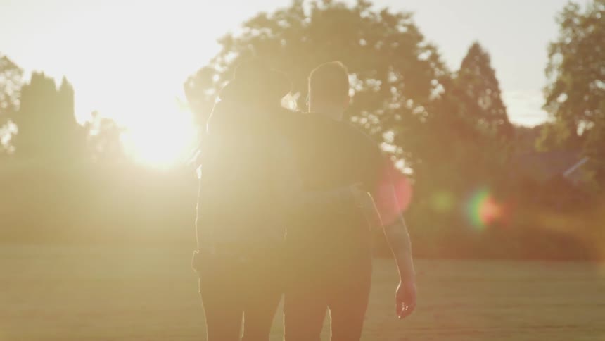 A couple walks through a field holding hands
