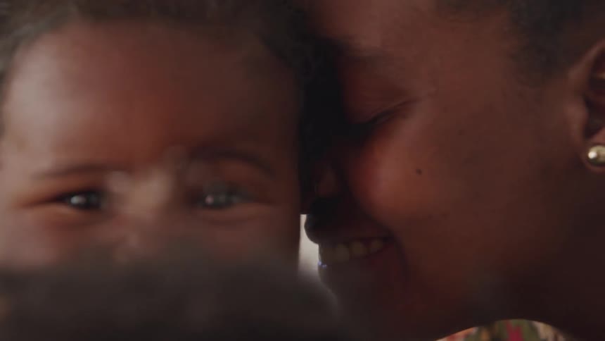 Two women laugh and play with baby