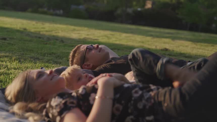 A family lays on a blanket in the grass
