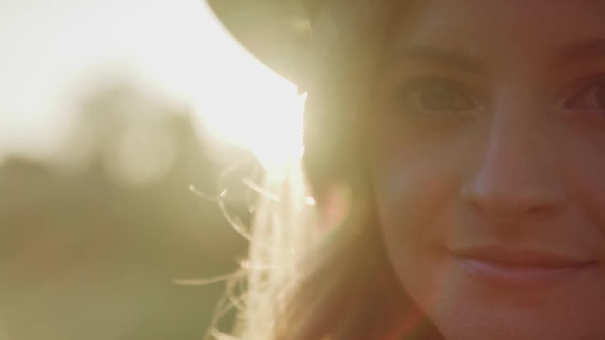 White woman smile to the camera with sun flare behind her