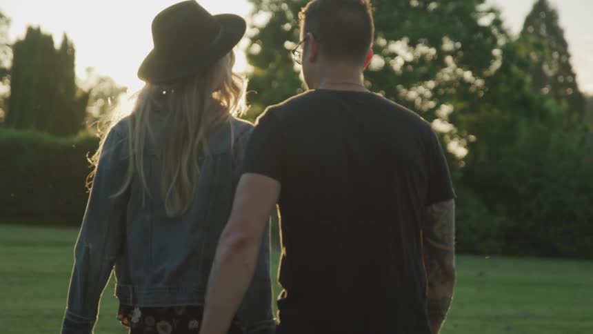 Couple walking outdoors holding hands and hugging at sunset