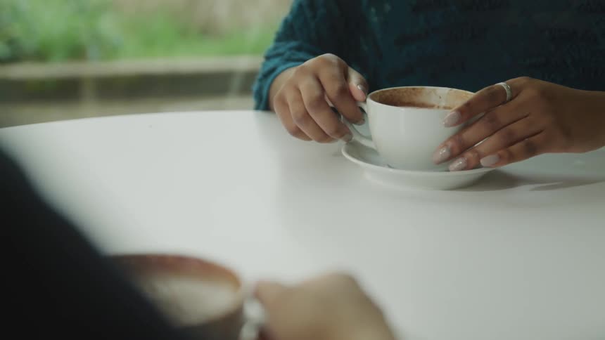 Two people are sitting down drinking coffee