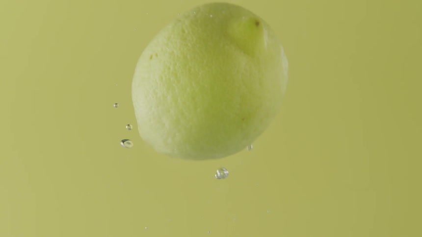 A lemon floating in water with bubbles