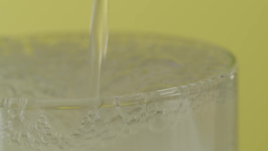 Clear soda is poured into a glass and fizzes as the glass fills