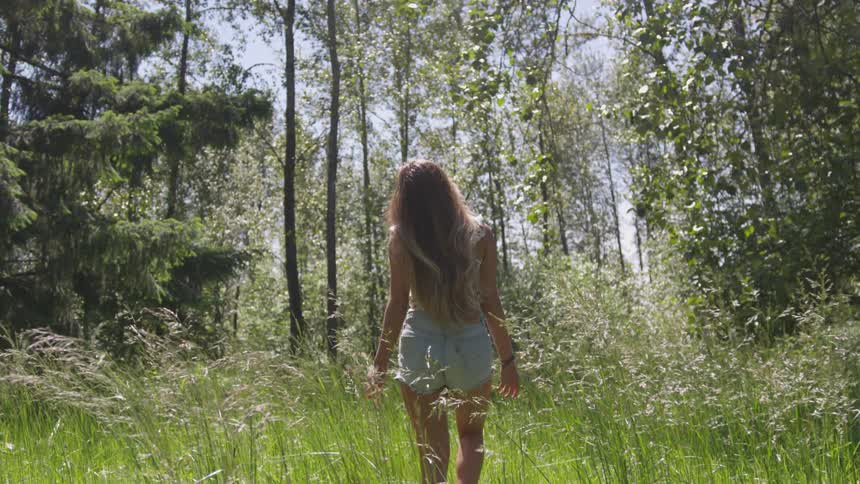 A woman walks through large grass