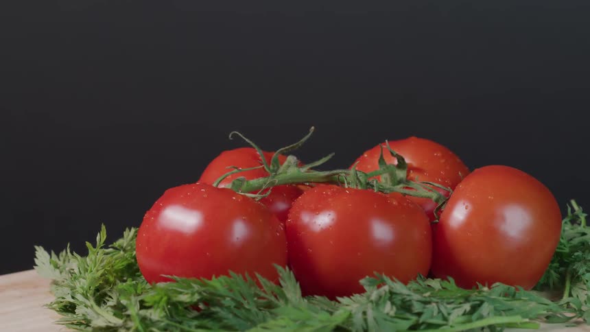 Five tomatoes on a cutting board with garnish