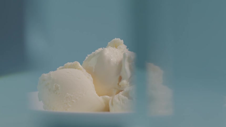 Vanilla ice cream sits in a white bowl as something nearby partially obfuscates it