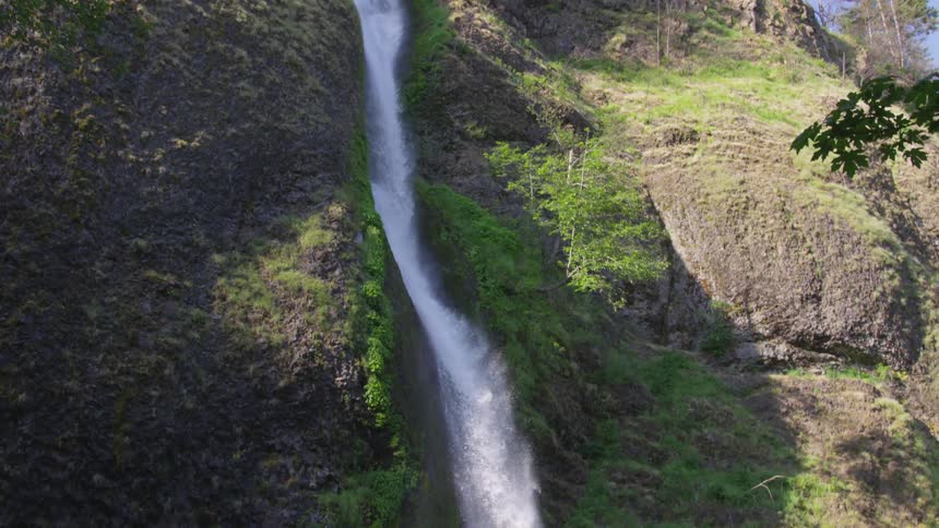A waterfall down a cliff covered in vegetation