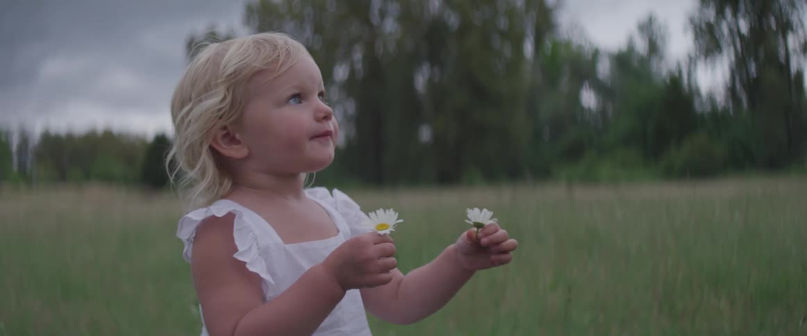 A child holds two flowers in hand