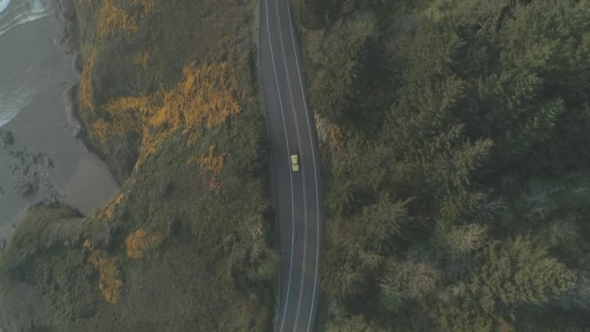 A car traveling along a gently curving road near the sea