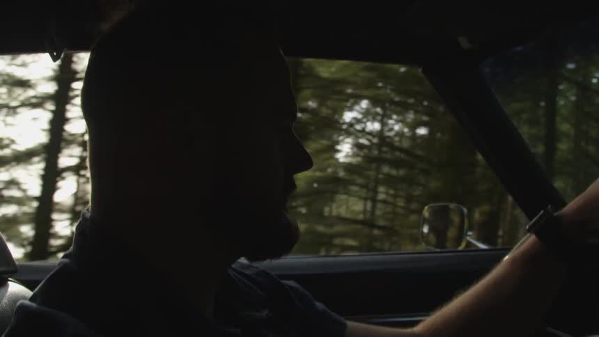 Male driving a car in the woods