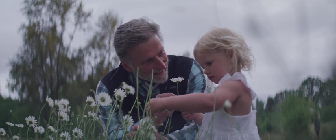 A man picks a flower for a little girl