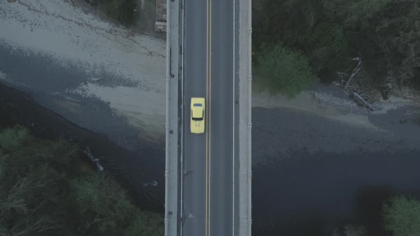 Aerial view of a car driving across a bridge