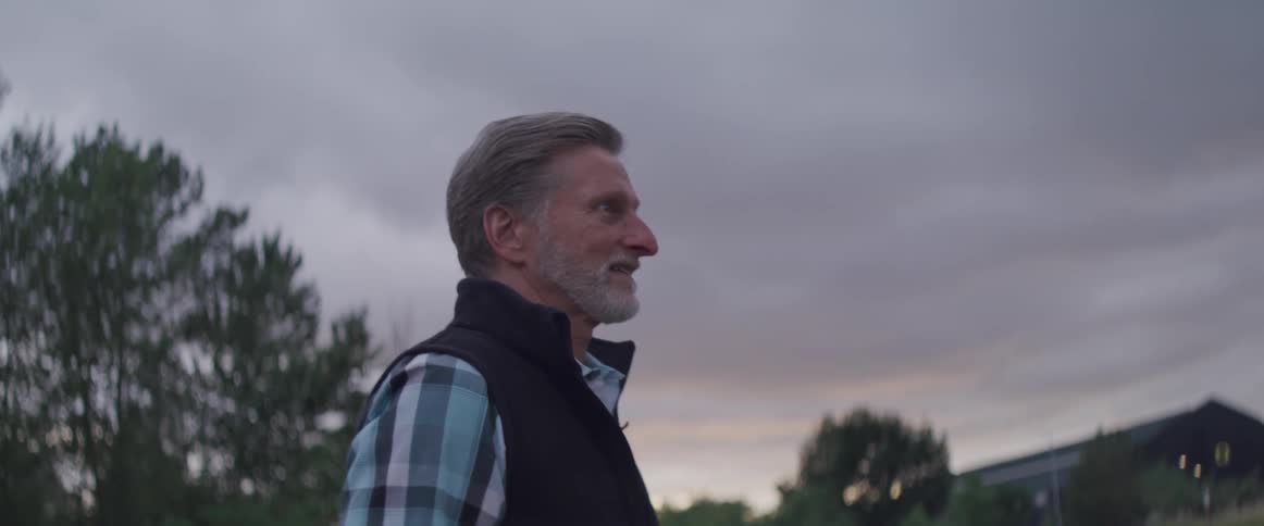 Old bearded man walks down the street at dusk on a cloudy day