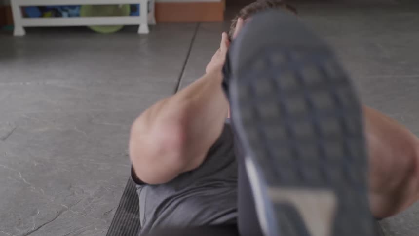 A man lies on a mat and does abdominal work