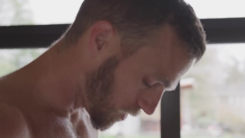 Man breathes heavily and sweats as he stands near a window