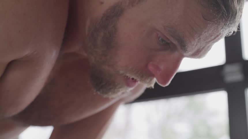 Shirtless blonde sweaty man takes deep breaths during workout by day
