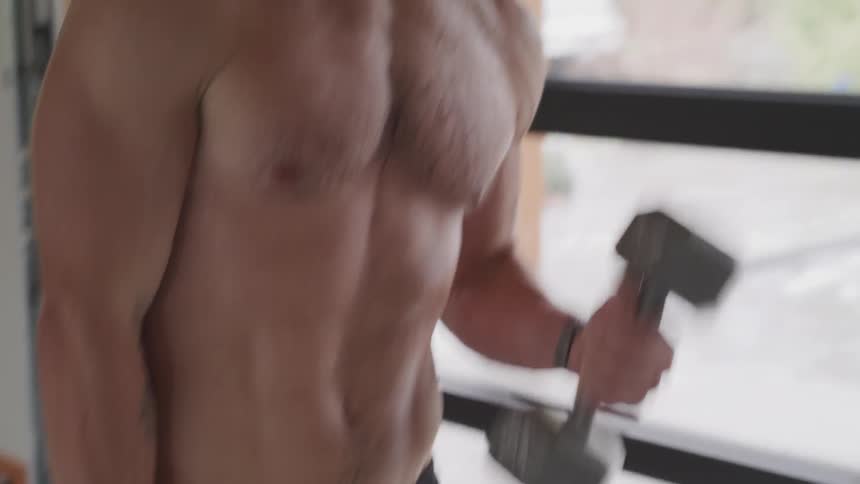A young man does bicep curls with dumbells
