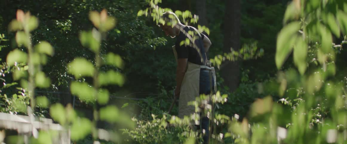 A man with a shovel works in his yard