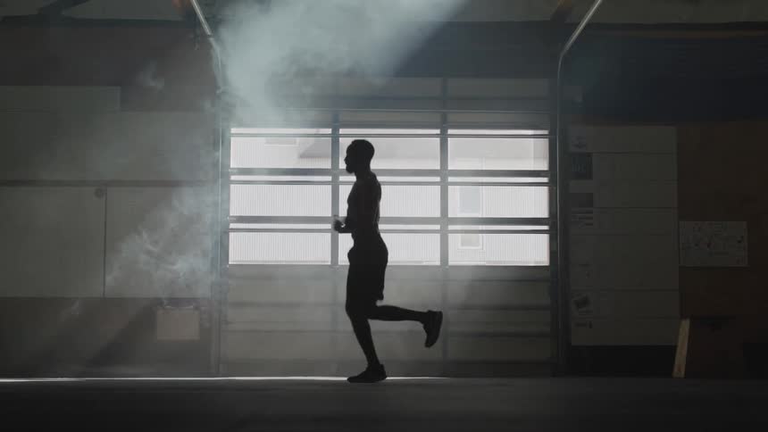 A man jumps rope in a dim room