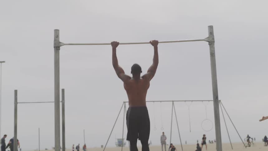 A man does pull ups at a beach gym