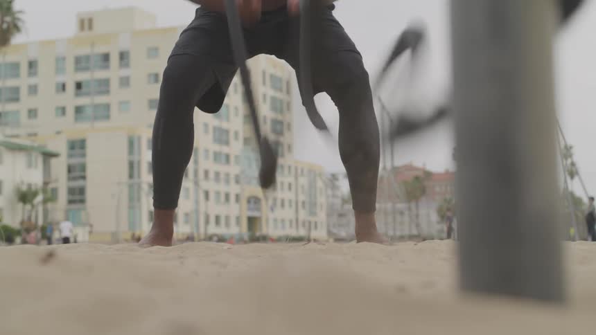 Man doing battle ropes at the beach
