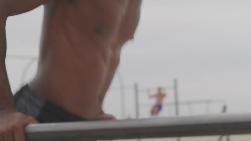 A man does dips on beach work out bars