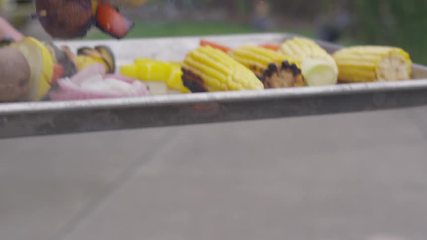 A pair of tongs grabbing cooked food off the grill