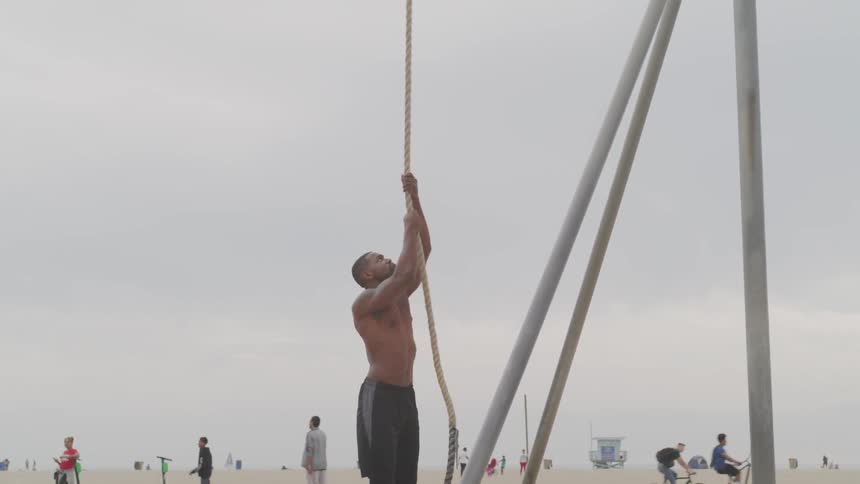 Man climbs a rope at the beach