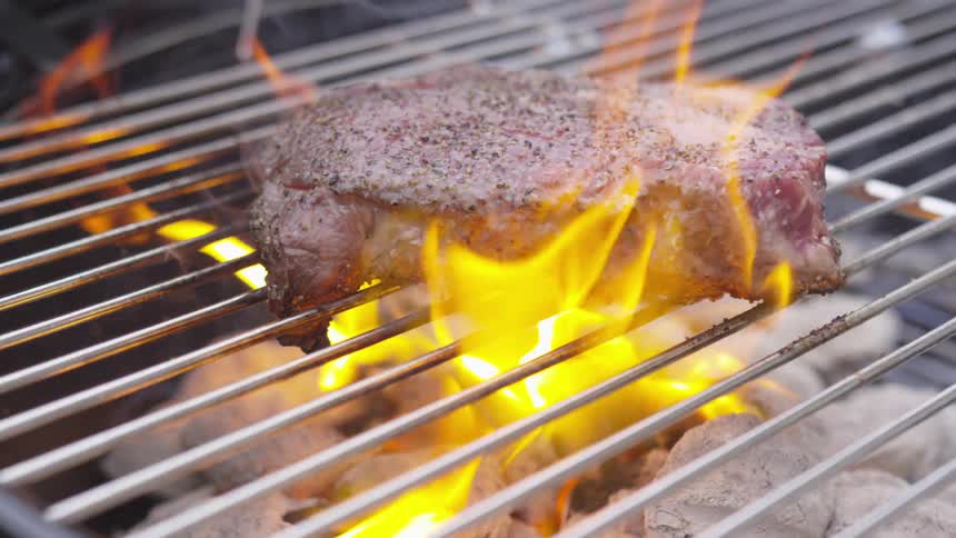 Flames surround the food cooking on the grill