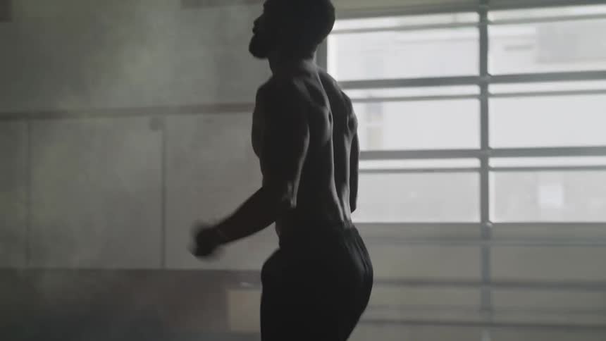 A shirtless black man works out by jumping rope