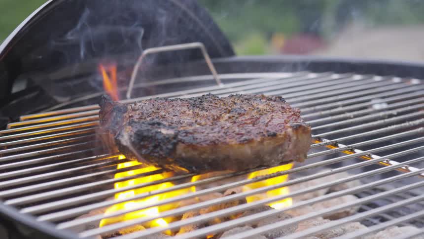 A steak cooks on a grill