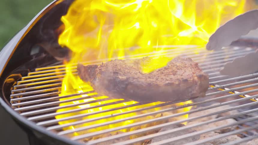 A steak being barbecued on a circular grill