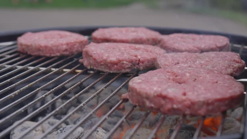 Hamburger patties grilling outdoors on barbeque grill