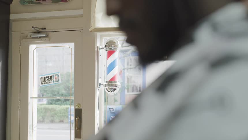 A black man sits in a barber shop