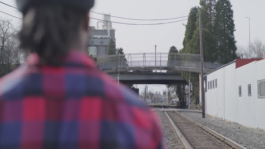 Man standing on train tracks looking at an overpass