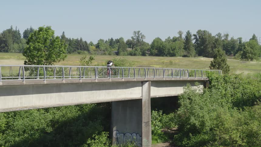 A man cycles across a bridge