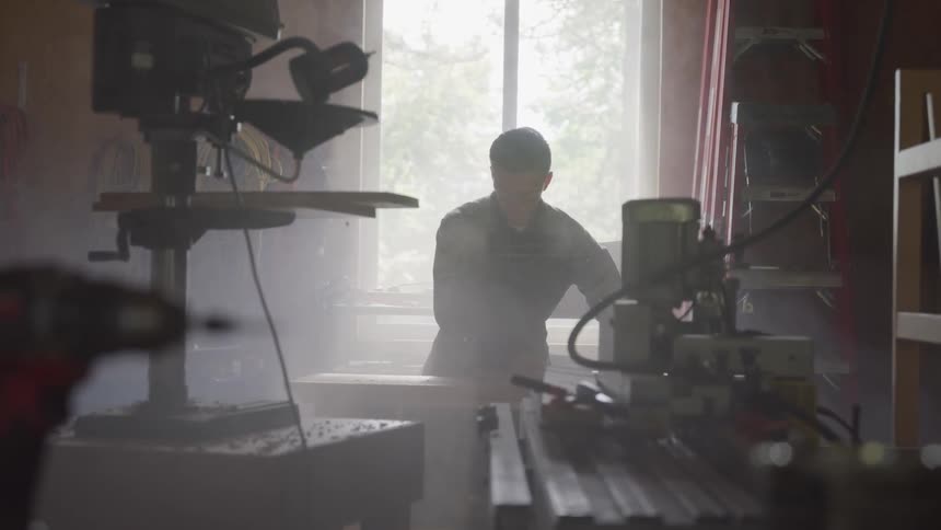 A man is standing in a workshop looking at something
