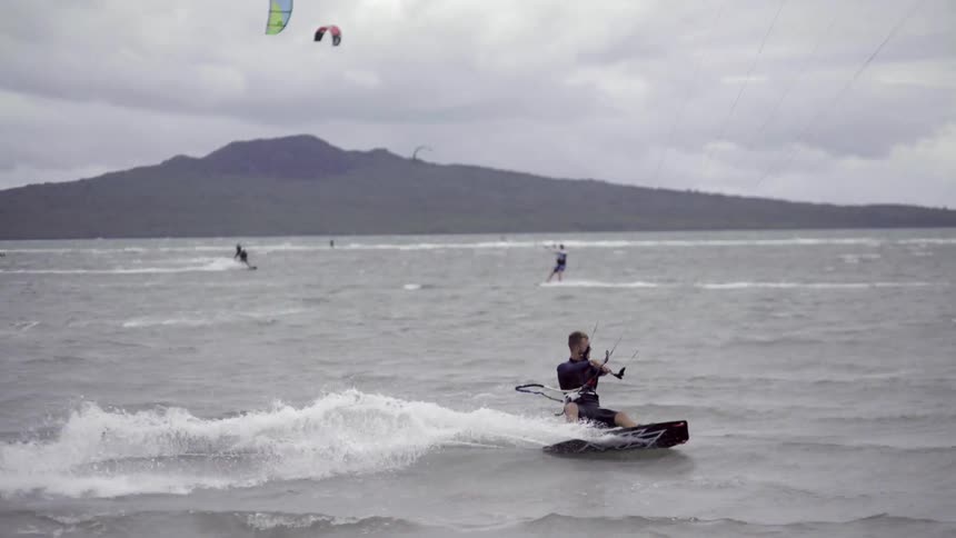 A person glides on a wakeboard behind a speedboat over open water, capturing motion, skill and outdoor water-sport action.